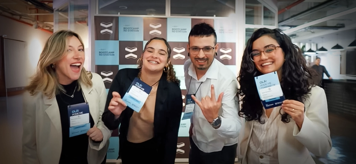 Equipe da Luzativo no Bootcamp RD Station: quatro profissionais sorrindo, com crachás, posando em frente ao backdrop do evento.